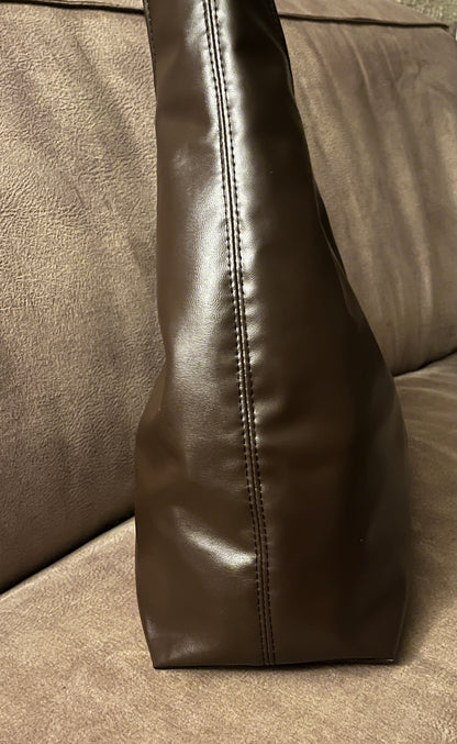 Deze handgemaakte hobo-tas is een perfecte balans tussen minimalistisch design en een subtiele wild touch.