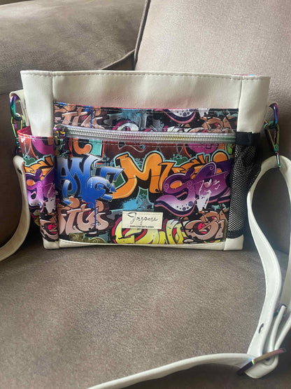  vrolijk gekleurde mini crossbody tas gemaakt van wit skai en waterafstotende stof met een kleurrijke graffiti print