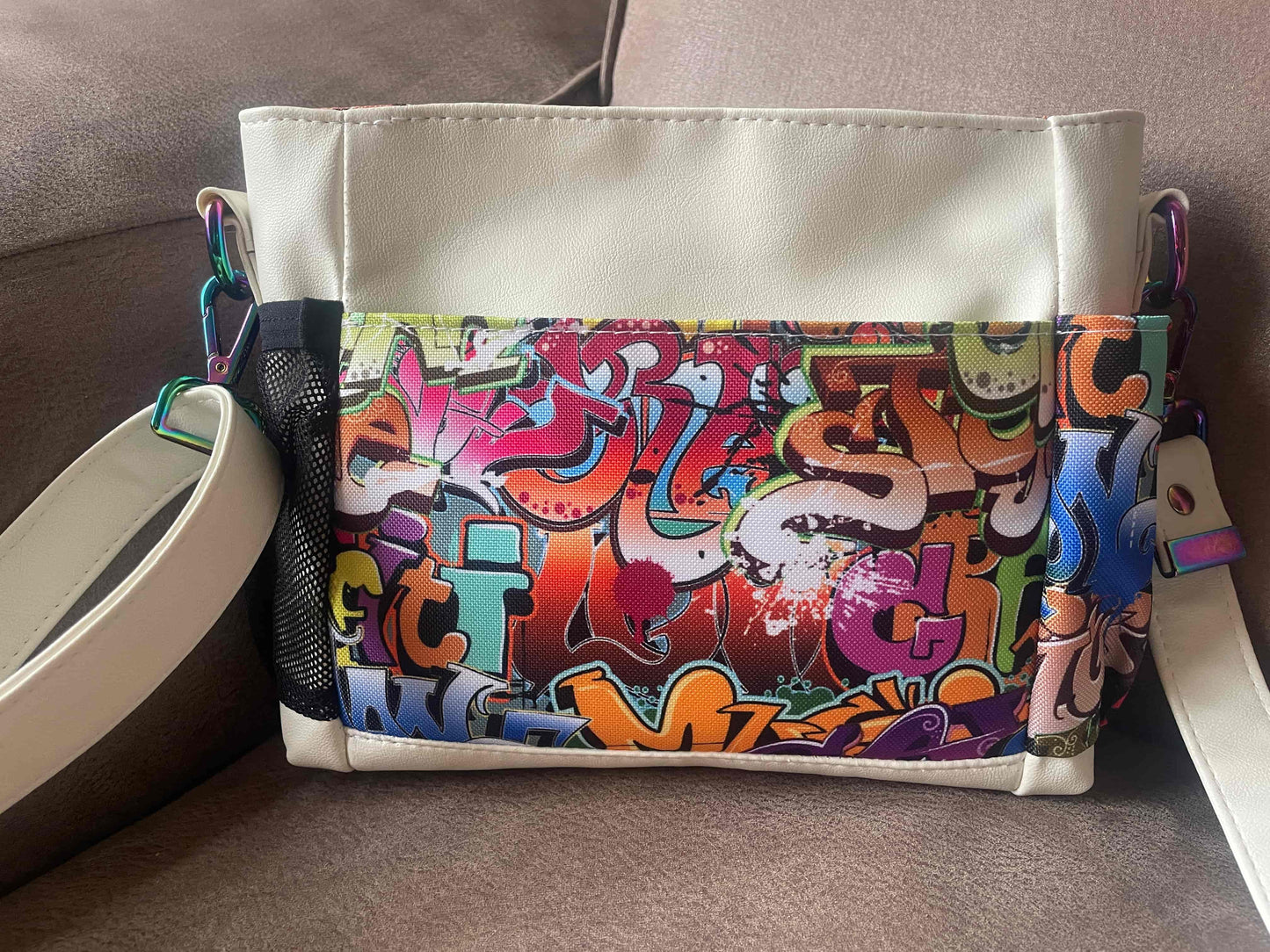  vrolijk gekleurde mini crossbody tas gemaakt van wit skai en waterafstotende stof met een kleurrijke graffiti print