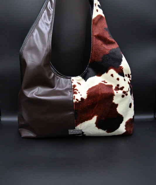 Luna Wild is een handgemaakte tas met een krachtige&nbsp;uitstraling en een zachte vorm. De combinatie van diepe tinten en speelse koeienprint maakt deze tas stoer én vrouwelijk tegelijk. Perfect voor elke dag, maar allesbehalve standaard.
