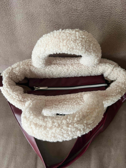 Zacht, stijlvol en met een luxe twist. Ivory & Wine is een handgemaakte teddy tas in een warme ivoortint, afgewerkt met een elegante bordeauxrode schouderband. 