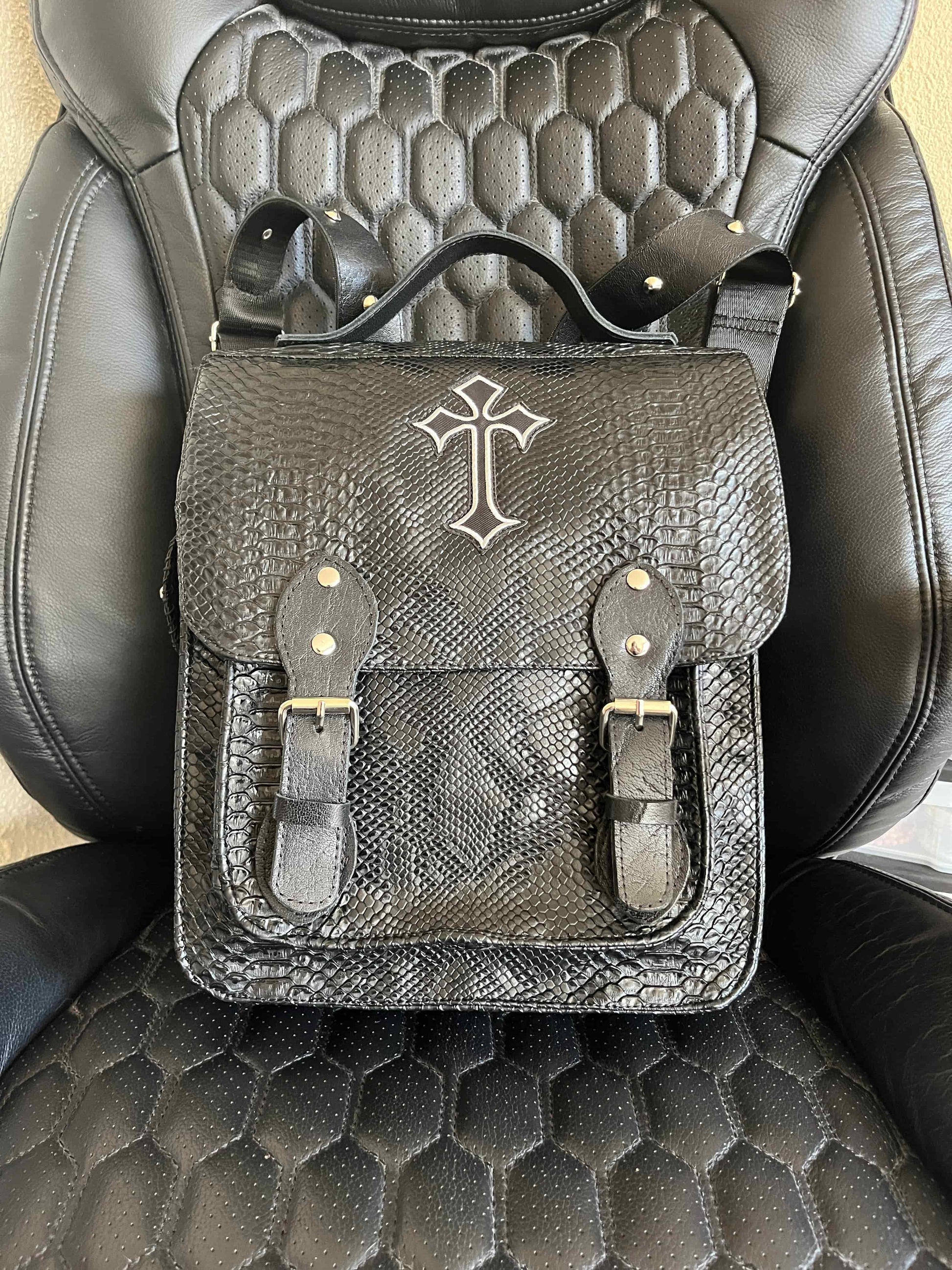 Handgemaakte stoere backpack tas in Gothic style met allerlei soorten studs en een kruis applicatie. De buitenkant van de tas is gemaakt van zwart kunstleer dat wat grove structuur heeft (krokodillenprint) en de binnenkant is van waterafstotende stof. De tas heeft een grote binnenvak en nog een klein binnenvakje met rits.