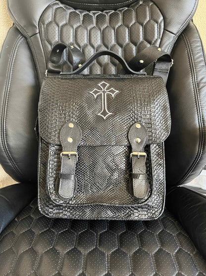 Handgemaakte stoere backpack tas in Gothic style met allerlei soorten studs en een kruis applicatie. De buitenkant van de tas is gemaakt van zwart kunstleer dat wat grove structuur heeft (krokodillenprint) en de binnenkant is van waterafstotende stof. De tas heeft een grote binnenvak en nog een klein binnenvakje met rits.