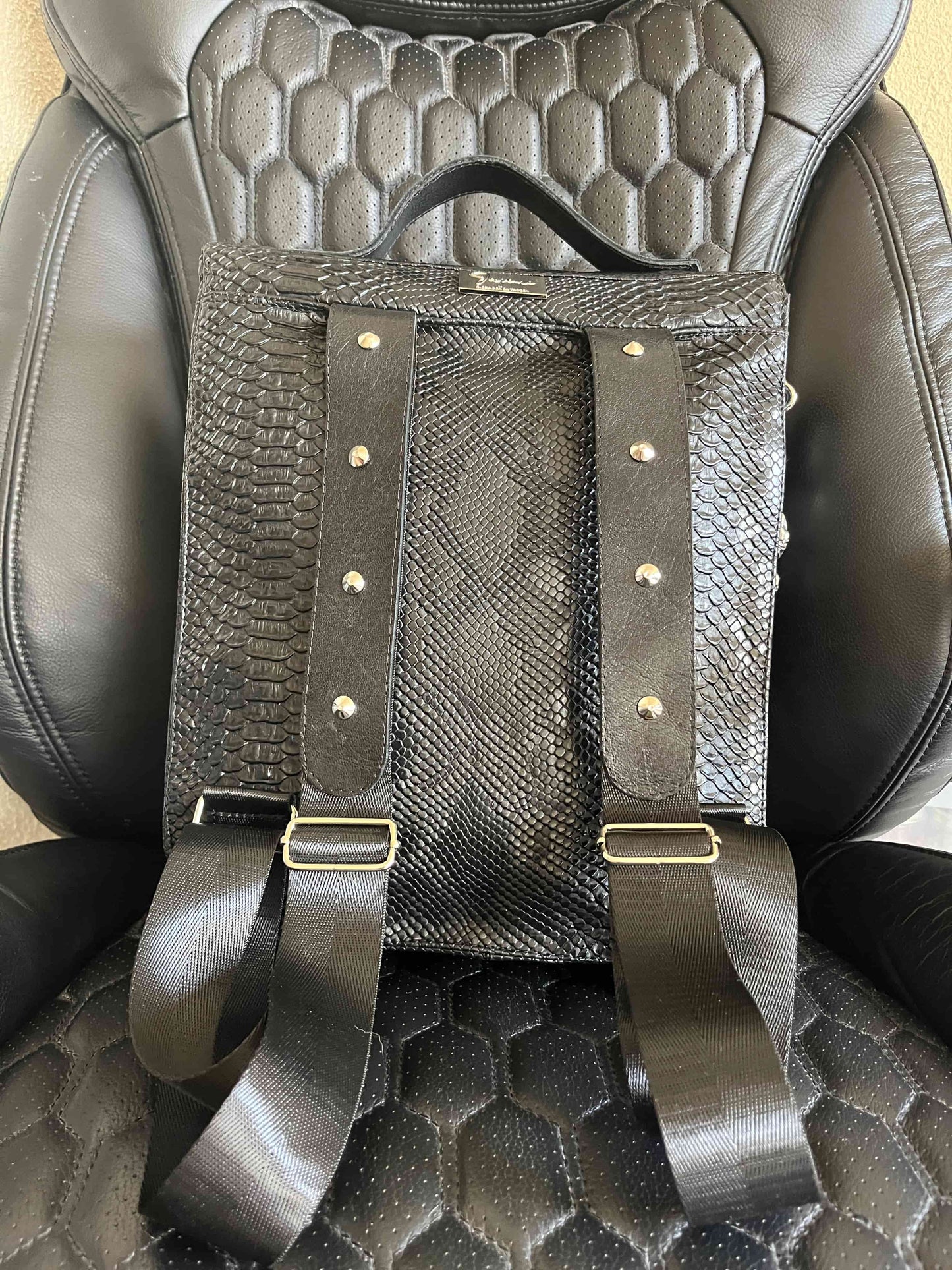Handgemaakte stoere backpack tas in Gothic style met allerlei soorten studs en een kruis applicatie. De buitenkant van de tas is gemaakt van zwart kunstleer dat wat grove structuur heeft (krokodillenprint) en de binnenkant is van waterafstotende stof. De tas heeft een grote binnenvak en nog een klein binnenvakje met rits.