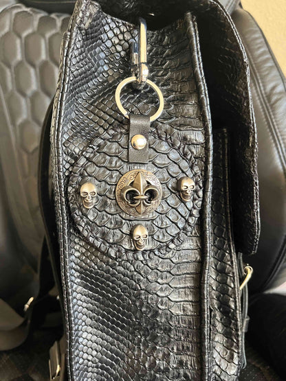Handgemaakte stoere backpack tas in Gothic style met allerlei soorten studs en een kruis applicatie. De buitenkant van de tas is gemaakt van zwart kunstleer dat wat grove structuur heeft (krokodillenprint) en de binnenkant is van waterafstotende stof. De tas heeft een grote binnenvak en nog een klein binnenvakje met rits.