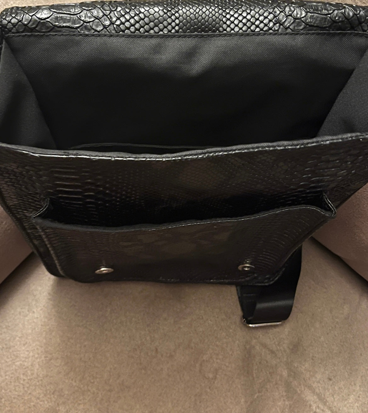 Handgemaakte stoere backpack tas in Gothic style met allerlei soorten studs en een kruis applicatie. De buitenkant van de tas is gemaakt van zwart kunstleer dat wat grove structuur heeft (krokodillenprint) en de binnenkant is van waterafstotende stof. De tas heeft een grote binnenvak en nog een klein binnenvakje met rits.