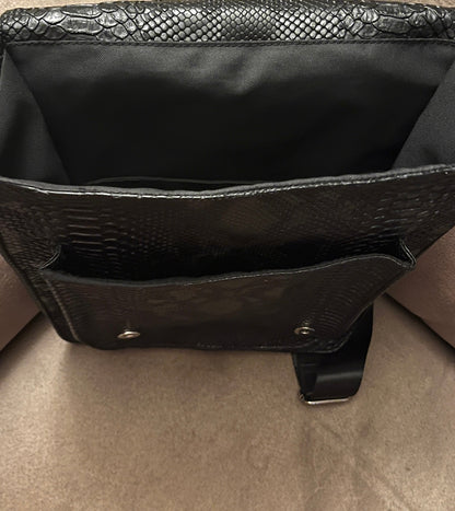 Handgemaakte stoere backpack tas in Gothic style met allerlei soorten studs en een kruis applicatie. De buitenkant van de tas is gemaakt van zwart kunstleer dat wat grove structuur heeft (krokodillenprint) en de binnenkant is van waterafstotende stof. De tas heeft een grote binnenvak en nog een klein binnenvakje met rits.
