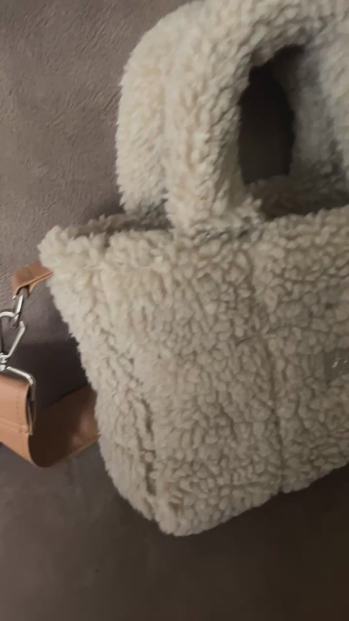 Omarm warmte en stijl met de Teddy Chic, de handgemaakte tas die comfort en elegantie perfect combineert. Gemaakt van superzachte Teddy-stof in een creamy beige tint, geeft deze tas elke outfit een knusse, luxueuze uitstraling