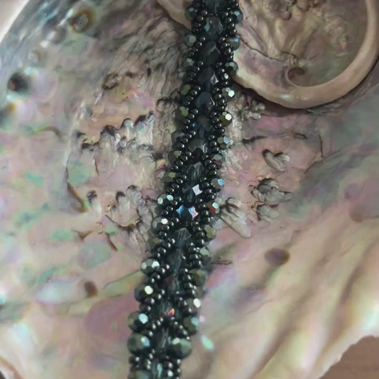 Een prachtige armband met diepe, glanzende groene tinten en elegante, gevlochten uitstraling die doet denken aan de oceaan, mystiek en natuur.